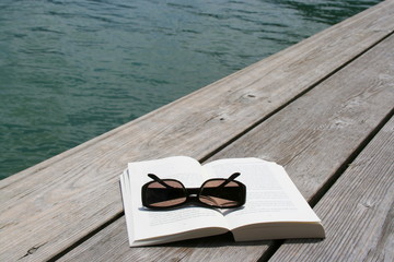 Buch und Sonnenbrille am Wasser