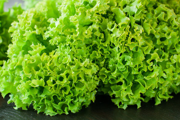 fresh green salad leaves (lettuce) on black wooden table