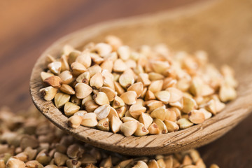 Buckwheat with a spoon on a wooden boards background