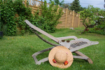 Liegestuhl im Garten mit Sonnenhut und Brille