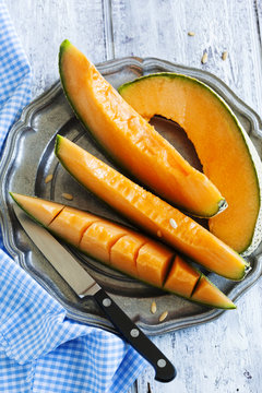 Cantaloupe melon slices on metal rustic plate. Top view