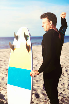 Handsome Young Surfer Zipping Up His Wetsuit