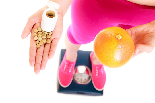 Woman holding vitamins and grapefruit. Health care.