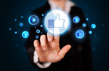 Young businesswoman pressing thumbs up button on modern social n