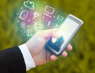 Hand holding smartphone with media icons