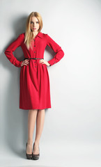 Expressive young model in red dress on gray background