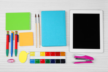 Digital tablet with stationery on wooden background