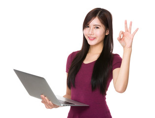 Young woman use of notebook computer and ok sign gesture