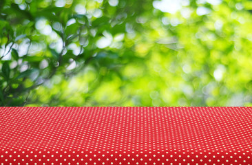 Table with red polka dot tablecloth over blur trees background