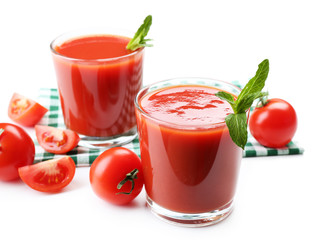 Glasses of fresh tomato juice on checkered napkin, isolated on white