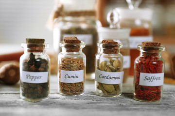 Assortment of spices in glass bottles on wooden background