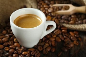 Cup of coffee with beans on table close up