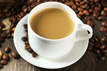 Cup of coffee with beans on table close up