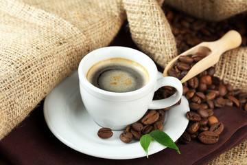 Cup of coffee with beans on table close up