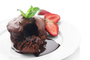 Chocolate fondant with strawberries on white plate, closeup
