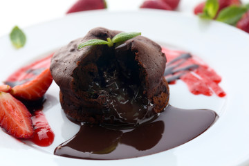 Chocolate fondant with strawberries on white plate, closeup