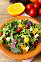 Tasty salad with arugula leaves in plate on wooden table, closeup
