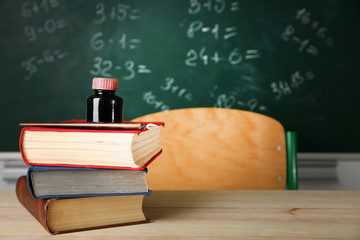 Stack of books on desk, on blackboard background