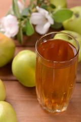 Glass of apple juice and apples on wooden table