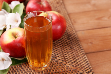 Glass of apple juice and apples on wooden table