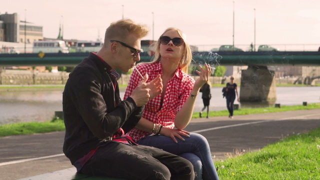 Couple smoking cigarettes and talking in the public place
