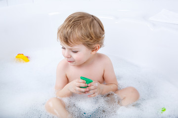 Adorable toddler boy having fun in bathtub