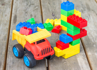 Plastic building blocks and toy truck on wooden background