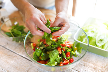 Unrecognizable young man preparing colorful vegetable salad