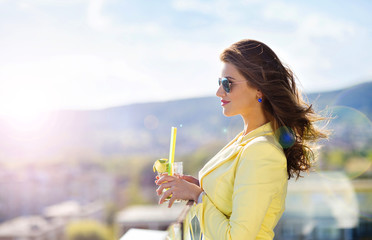 Attractive young woman with a drink on a terrace of a bar