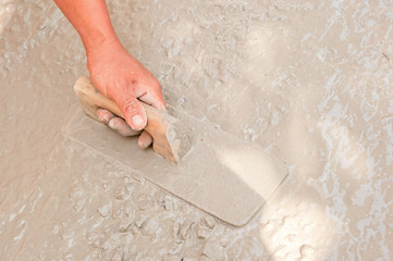 Asian plasterer hand plastering a floor
