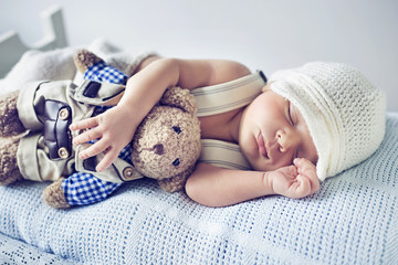 Newborn child sleeping with a teddy bear