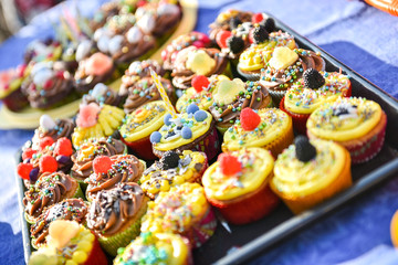 Delicious colorful cupcakes with a birthday candle are on a plat