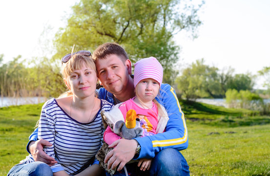 Portrait of Small Family Sitting in Grass by River