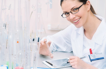 young smiling woman scientist working and observing liquid at th