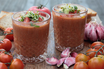 Two glasses of freshly prepared gazpacho with vegetable topping.
