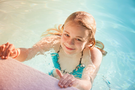 Beautiful teenage blond girl swims in pool