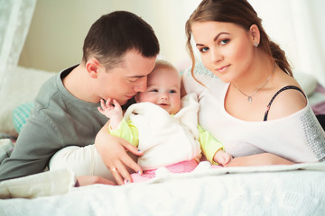 Closeup of young family with baby girl on the bed against