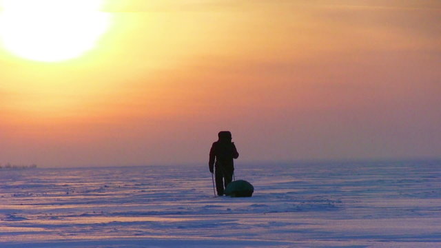 One man go to sunset on snow desert