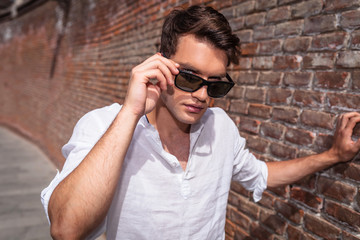 Handsome young man taking off his sunglasses.