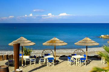 Spiaggia con geometrie di ombrelloni, tavolini e ruote di carro