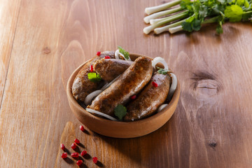 Homemade sausages grilled in a clay plate kupaty