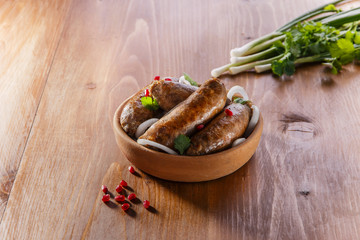 Homemade sausages grilled in a clay plate kupaty