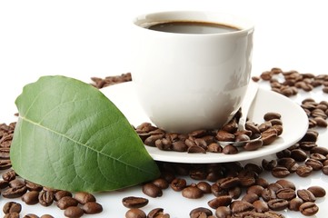 Scattered coffee beans with cups of coffee and leaf