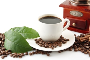 Scattered coffee beans with cups of coffee and leaf