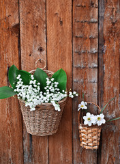 Two baskets of lilies and daffodils on a wooden background