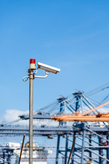 Fototapeta premium CCTV cameras with warning lights on steel pole and blurred crane