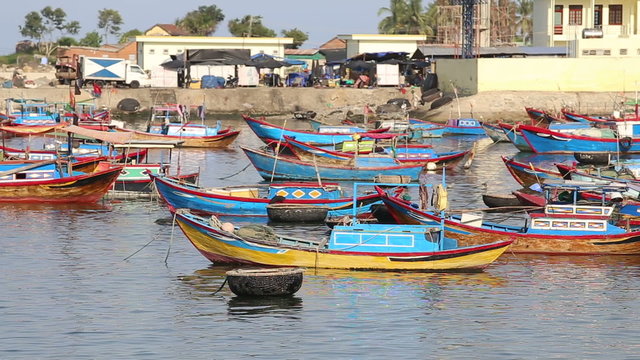 fishing boats roll in bay against small village at dawn	