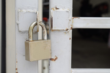 Old padlock hanging on gray metal door