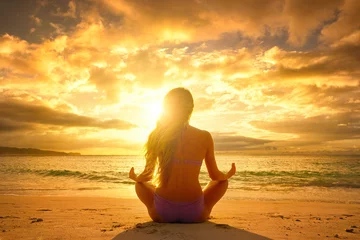 Foto op Plexiglas Young woman relaxing in lotus position during a beautiful sunset © soft_light
