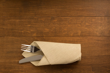 knife and fork at napkin on wood